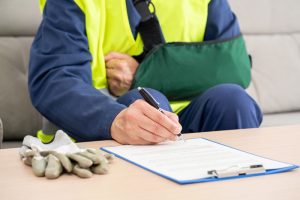 Front view of a repairman with sling signing contract at home